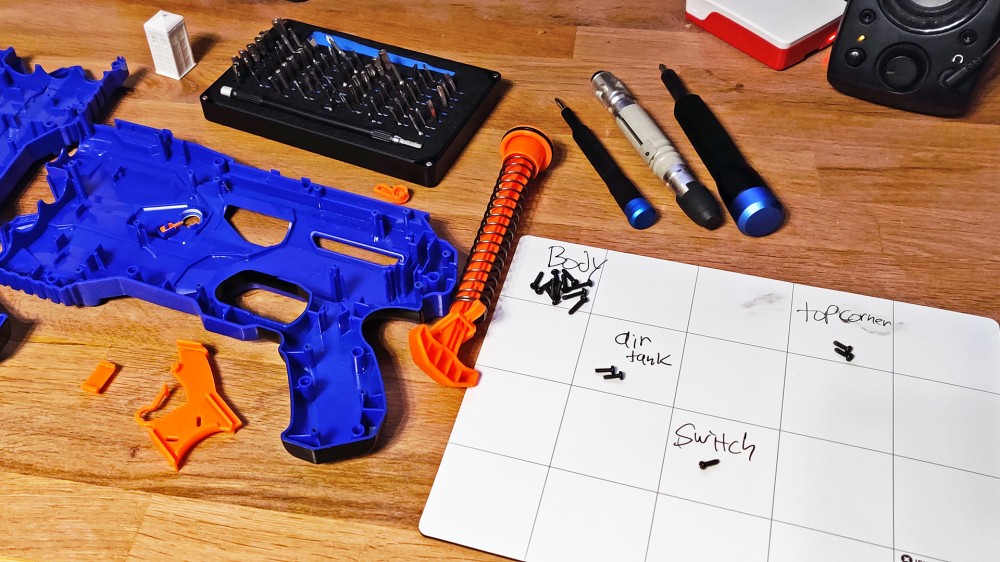 Dos kits iFixit rodeados por una pistola Nerf destrozada.