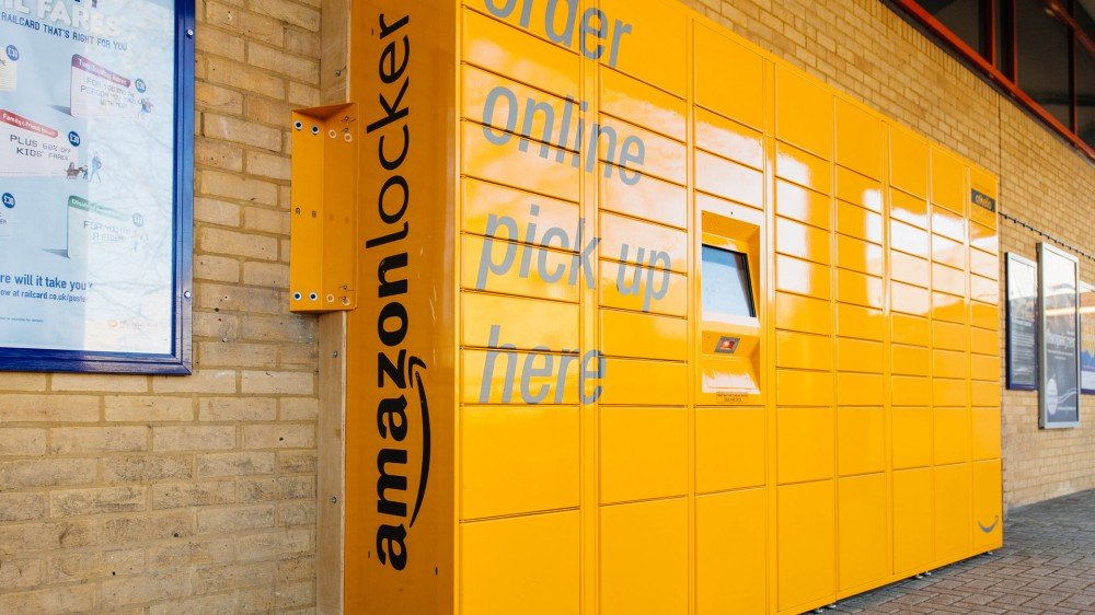 Un sistema Amazon Locker amarillo a lo largo de una pared de ladrillos.