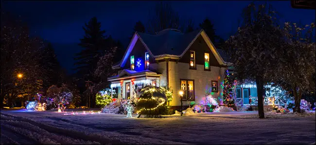 Casa privada cubierta de nieve con luces y adornos navideños brillantes