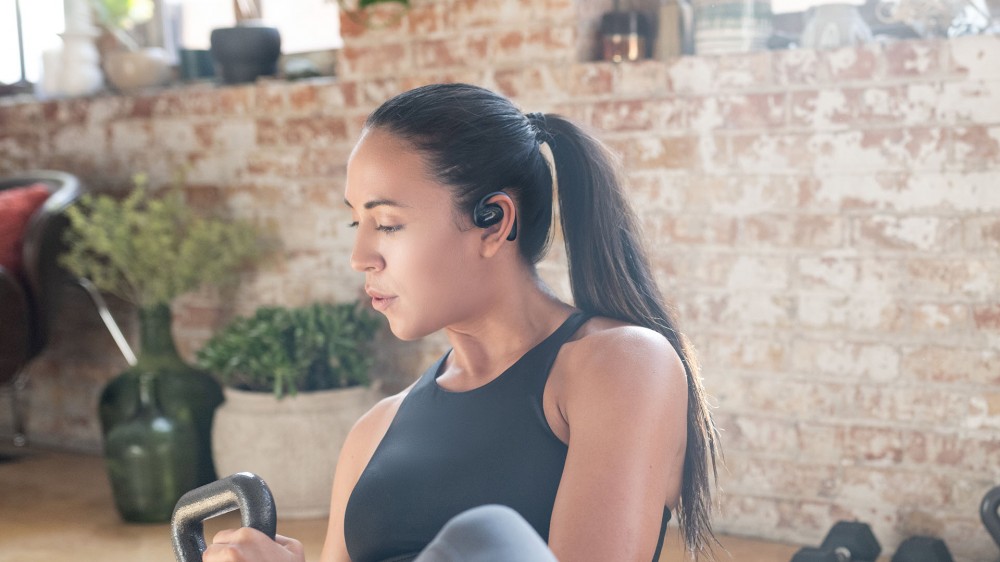 Una mujer hace ejercicio mientras usa los auriculares abiertos Bose Sports