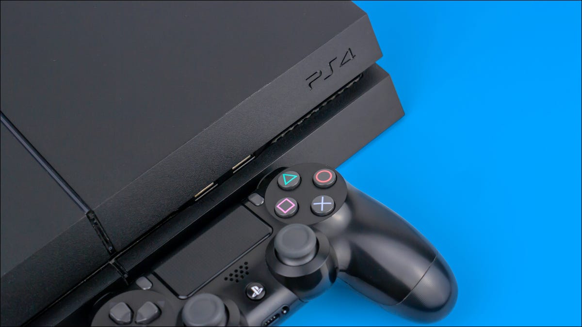 Una consola Sony PS4 con un controlador DualShock al lado sobre un fondo azul.